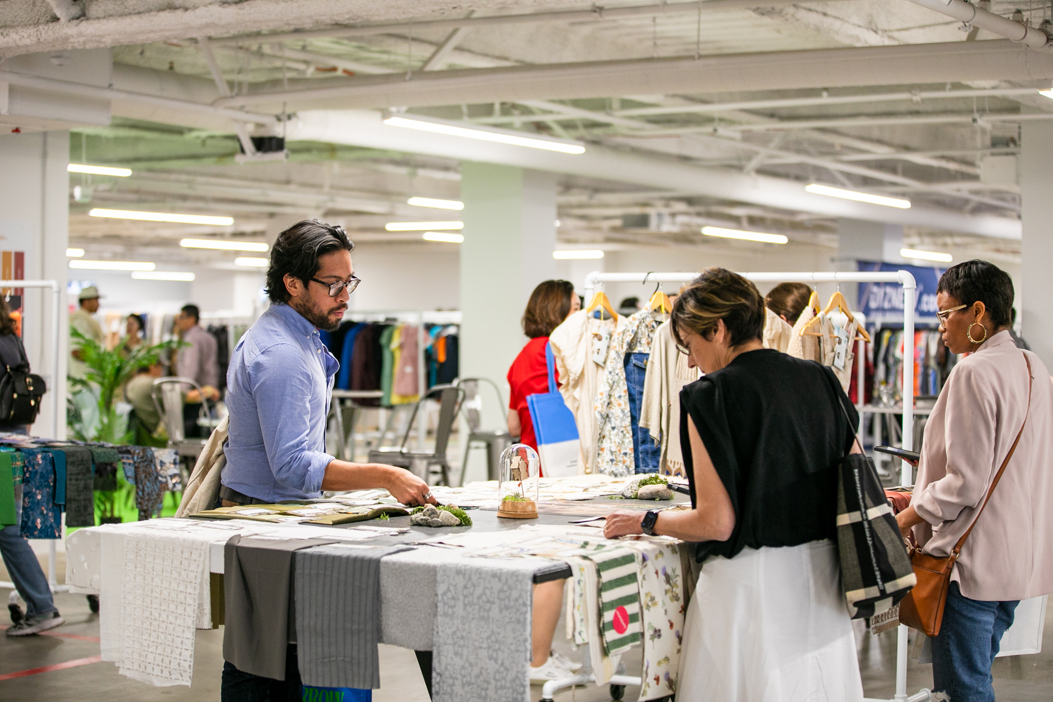 Visitors examining fabric samples and textiles at a booth during Texworld New York