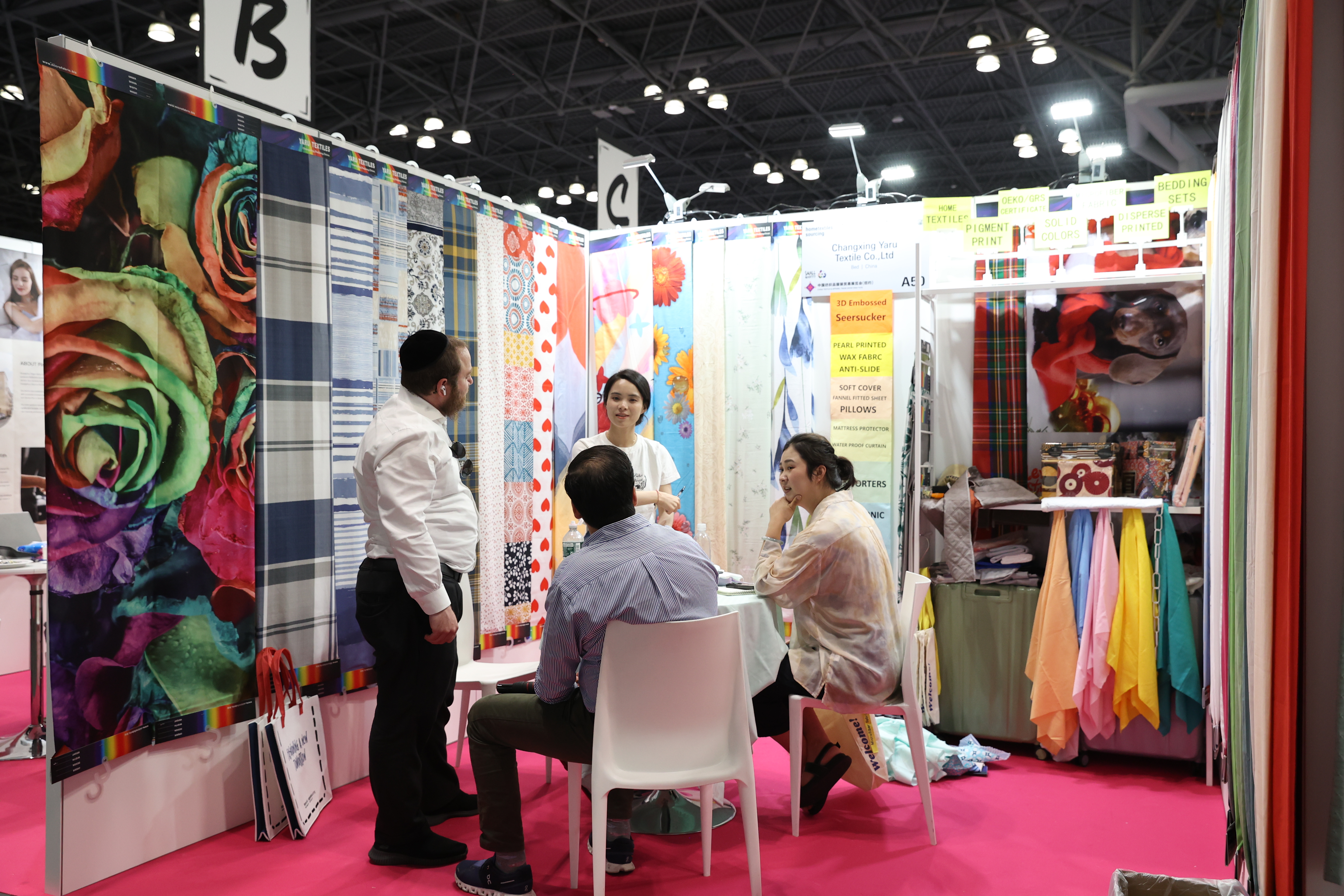 Trade show attendees discussing textile designs at a fabric booth during Texworld New York.