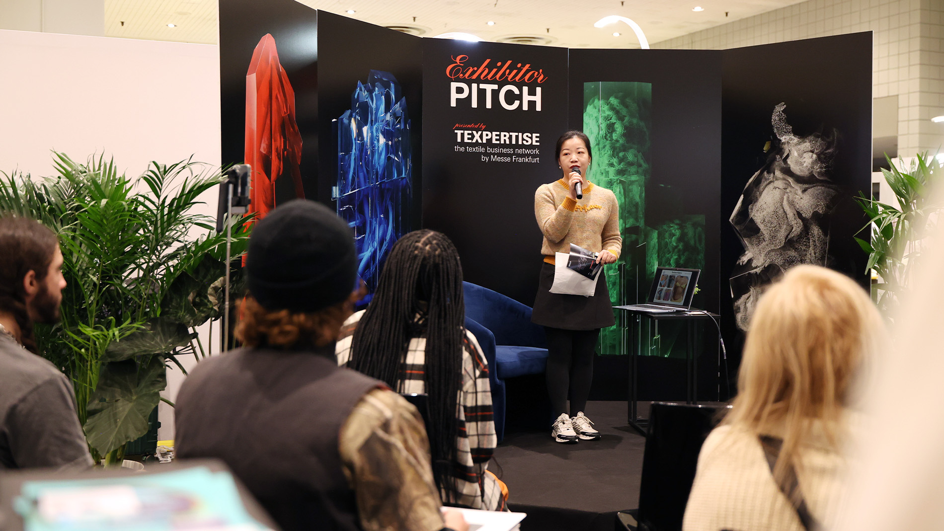 Panel speaker holding a microphone during a discussion at Texworld New York special feature event.