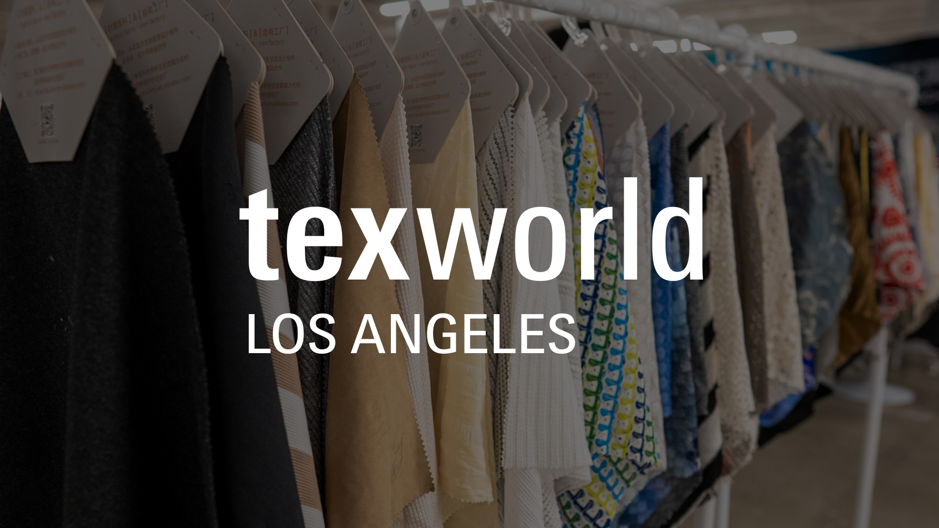 Visitors examining fabric samples and textiles at a booth during Texworld New York